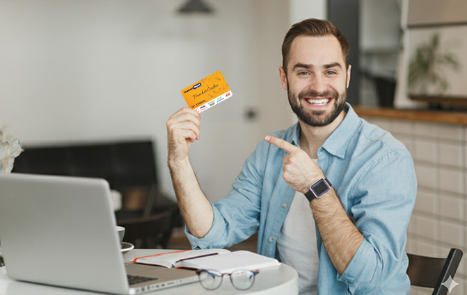 Bărbat în fața unui laptop, zâmbind și ținând în mână un Card Cadou Multibrand Vouchers Depot.